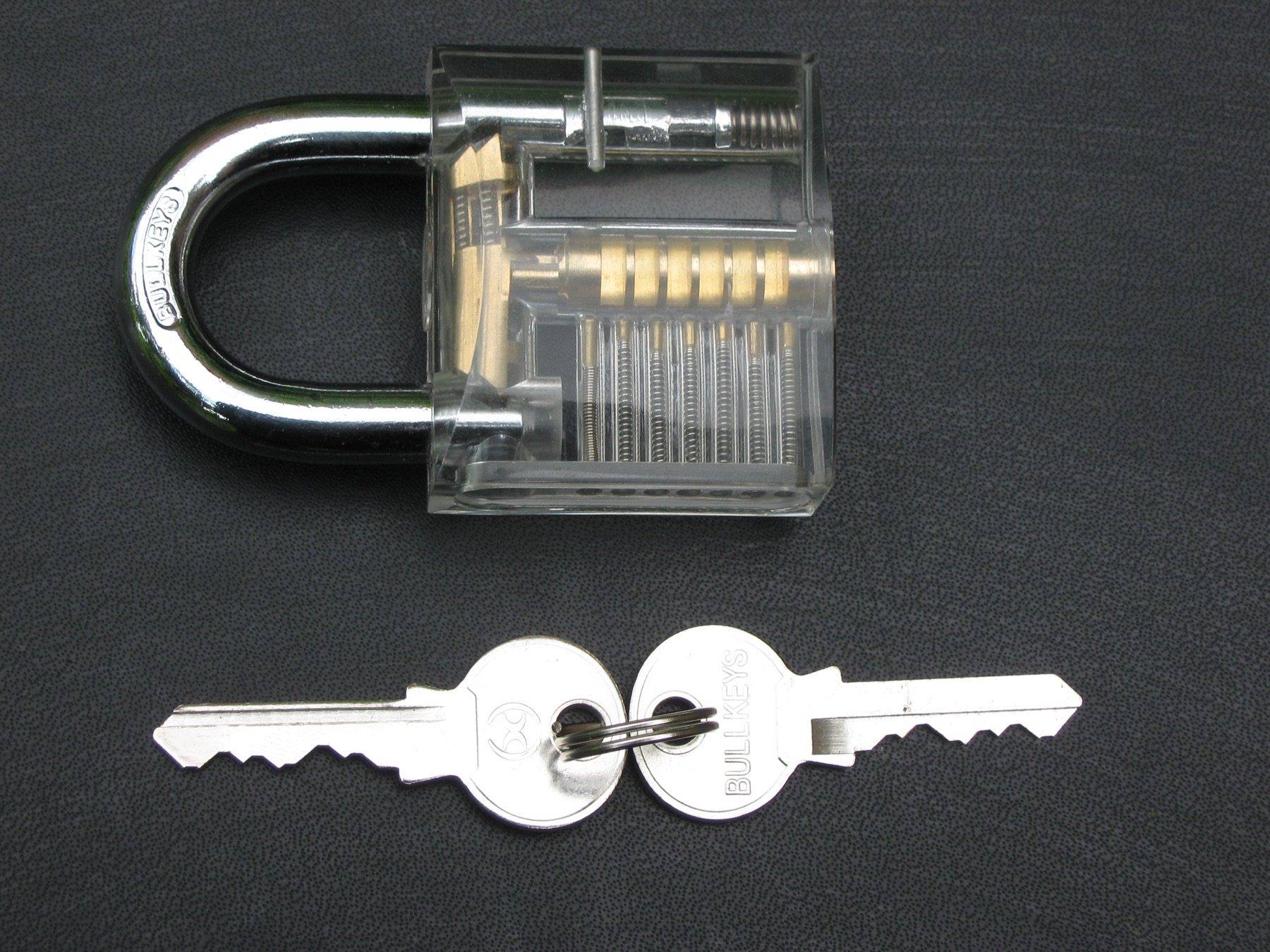 Transparent padlock and keys showing the internal lock cylinder